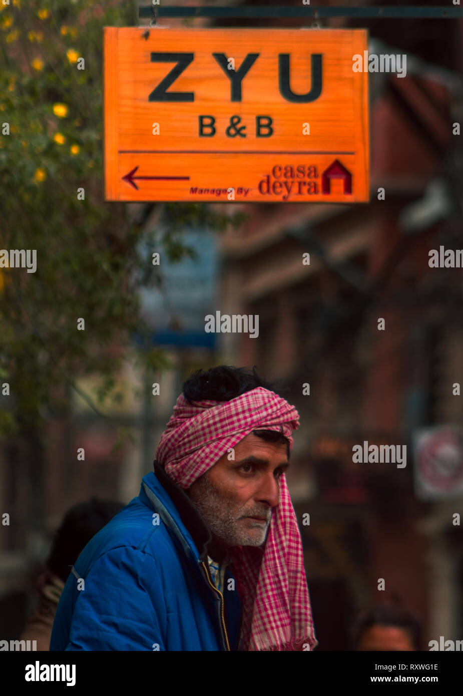 A local street vendor stares at the people passing by one early morning Stock Photo