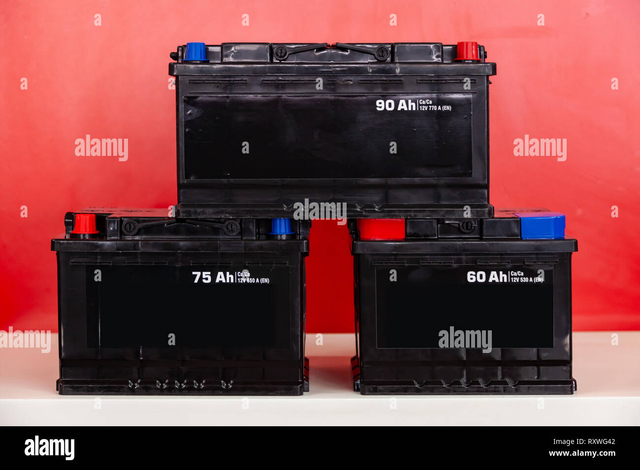 Three new black rechargeable batteries for 60, 75, 95 ampere hours, stand  pyramid on each other on a red background with white inscriptions Stock  Photo - Alamy