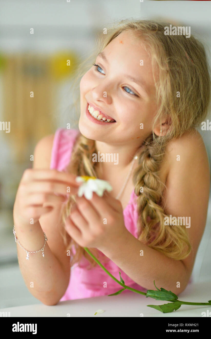 Portrait of beautiful little girl with braids holding white flower Stock Photo