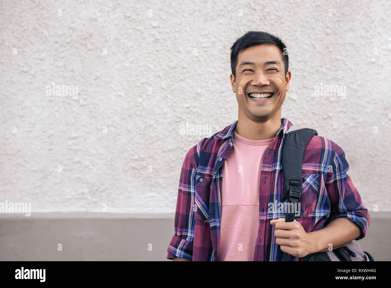 Young Asian man standing outside in the city and laughing Stock Photo