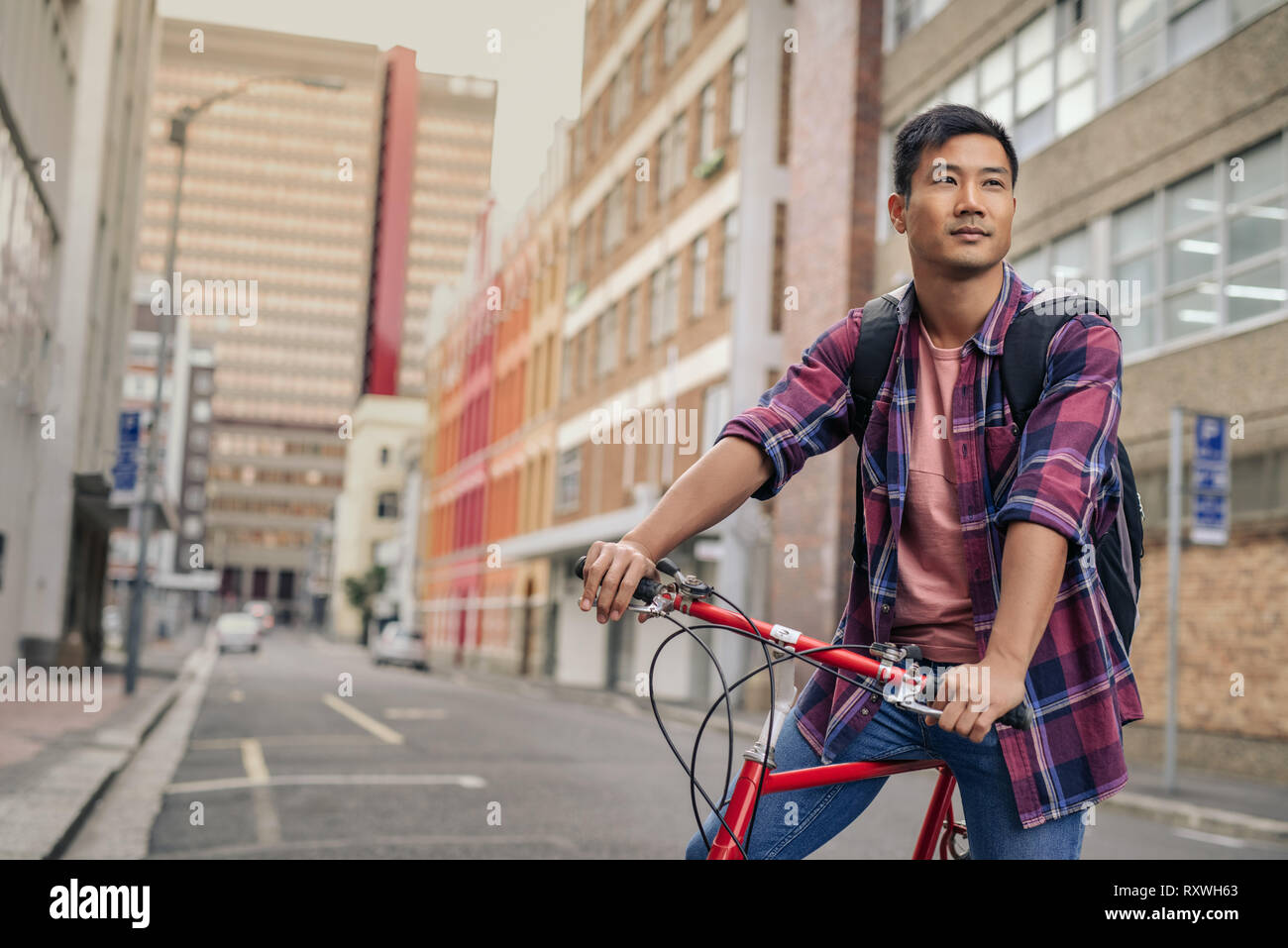 Young Asian man sitting on his bicycle in the city Stock Photo