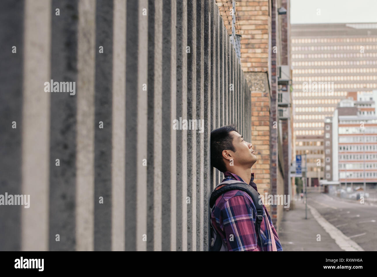Content young Asian man leaning against a wall Stock Photo