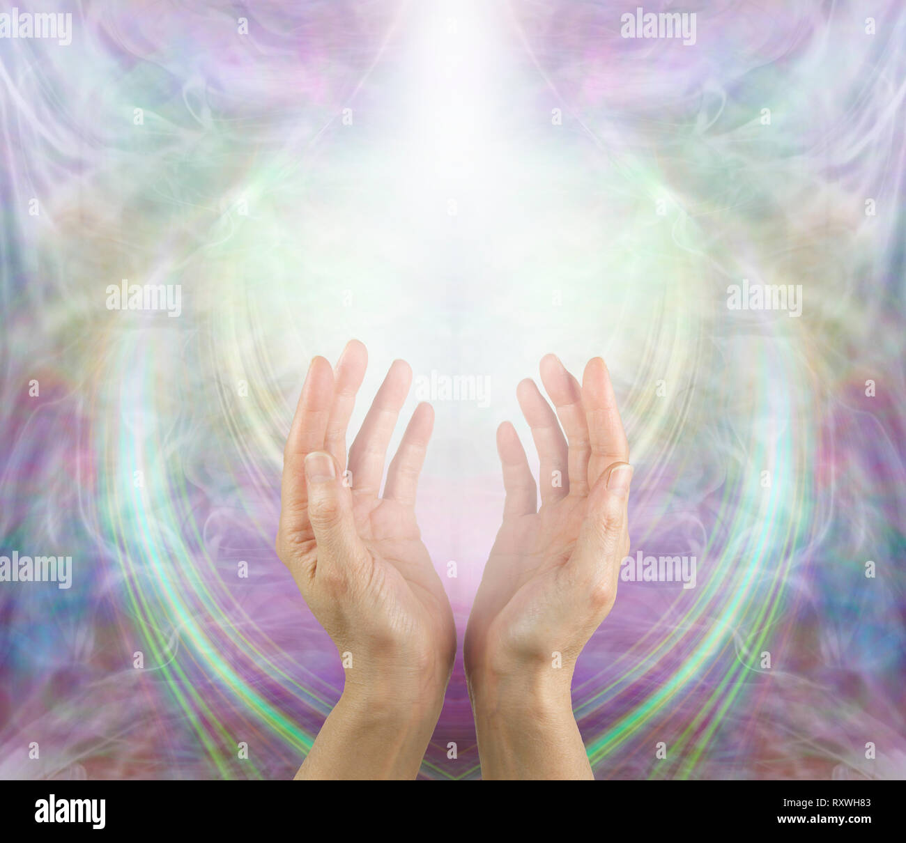 Ask Believe Receive in the Power of Love - female with hands reaching up into a white light against a beautiful angelic ethereal cup shaped background Stock Photo
