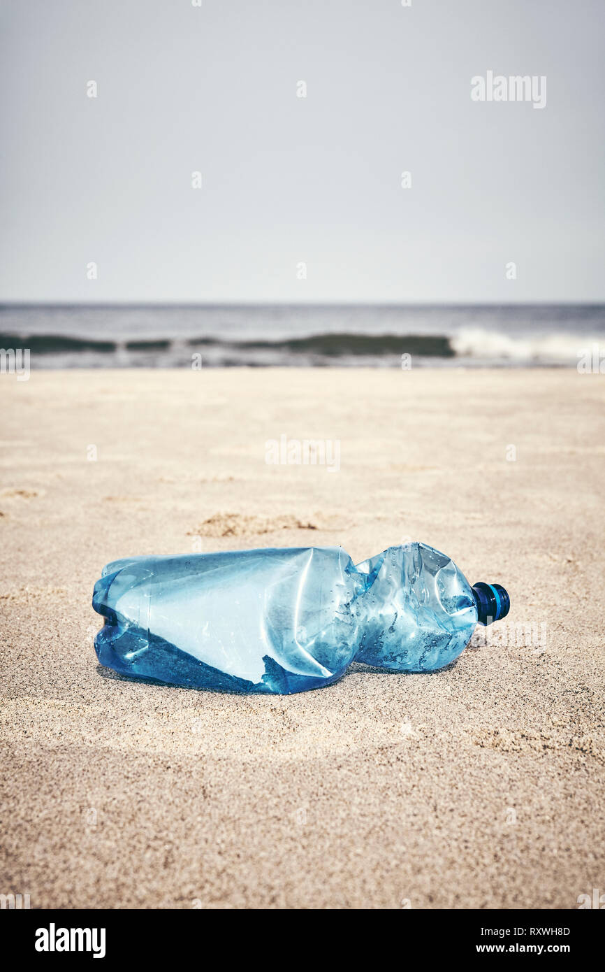 Empty plastic bottle on a beach, selective focus, color toning applied. Stock Photo