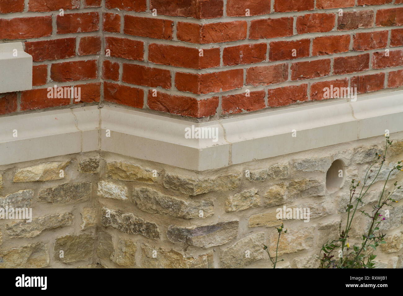 Hand Made Red bricks meet stone, divided by concrete Lintel Stock Photo