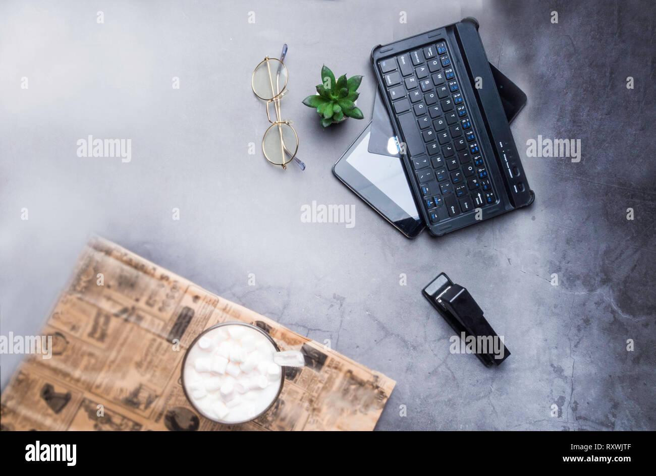 office table, coffee, glasses, stapler, cactus, laptop, credit card on concrete table with newspaper Stock Photo