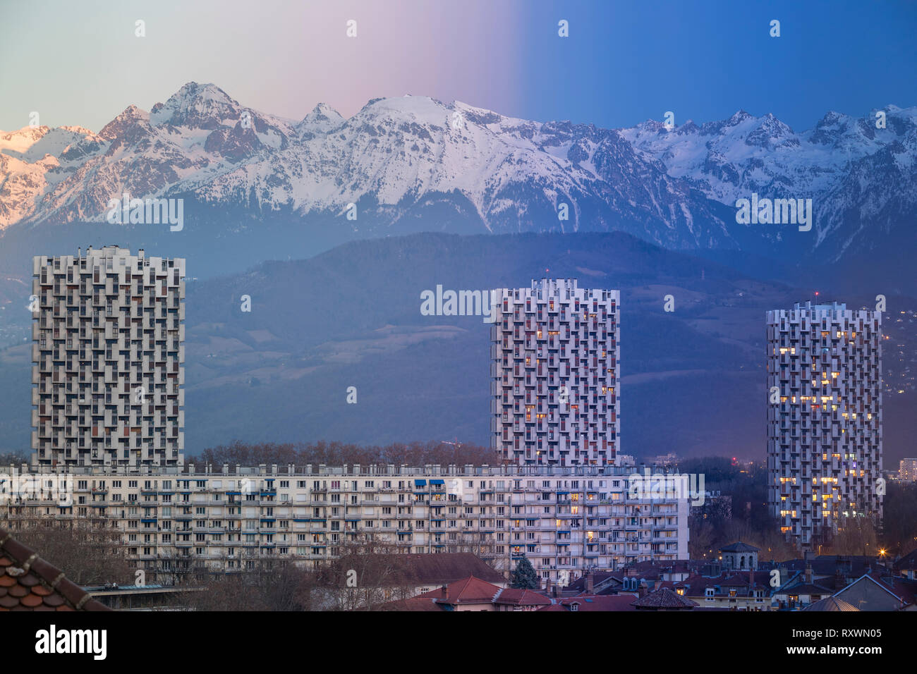 Grenoble, France 2019 : Day to night on the three towers of the ile verte neighbourhood in front of the belledonne mountains. alpenglow to blue hour Stock Photo
