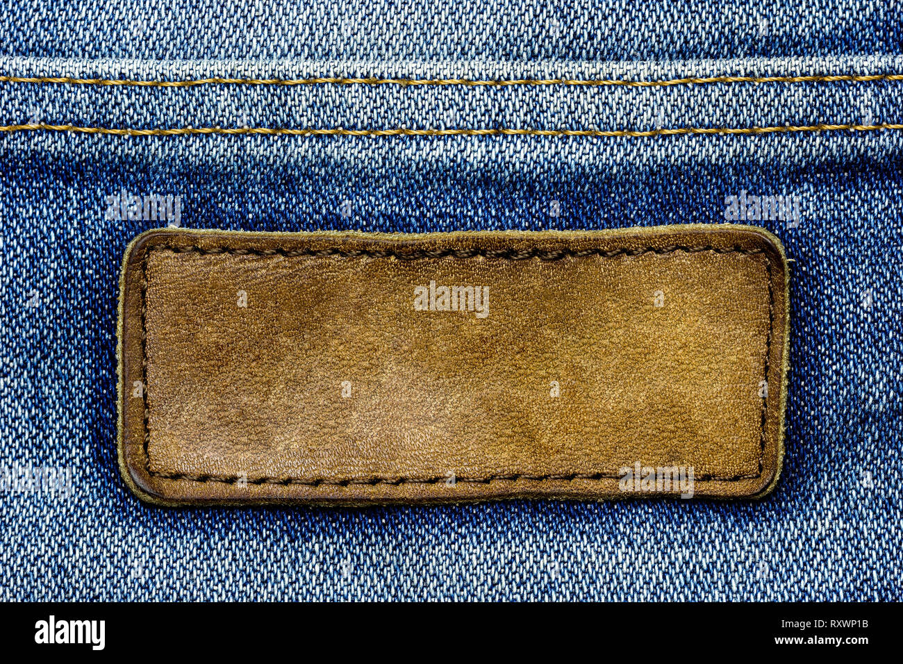 Blank brown leather label on vintage blue jeans. Suitable for ...