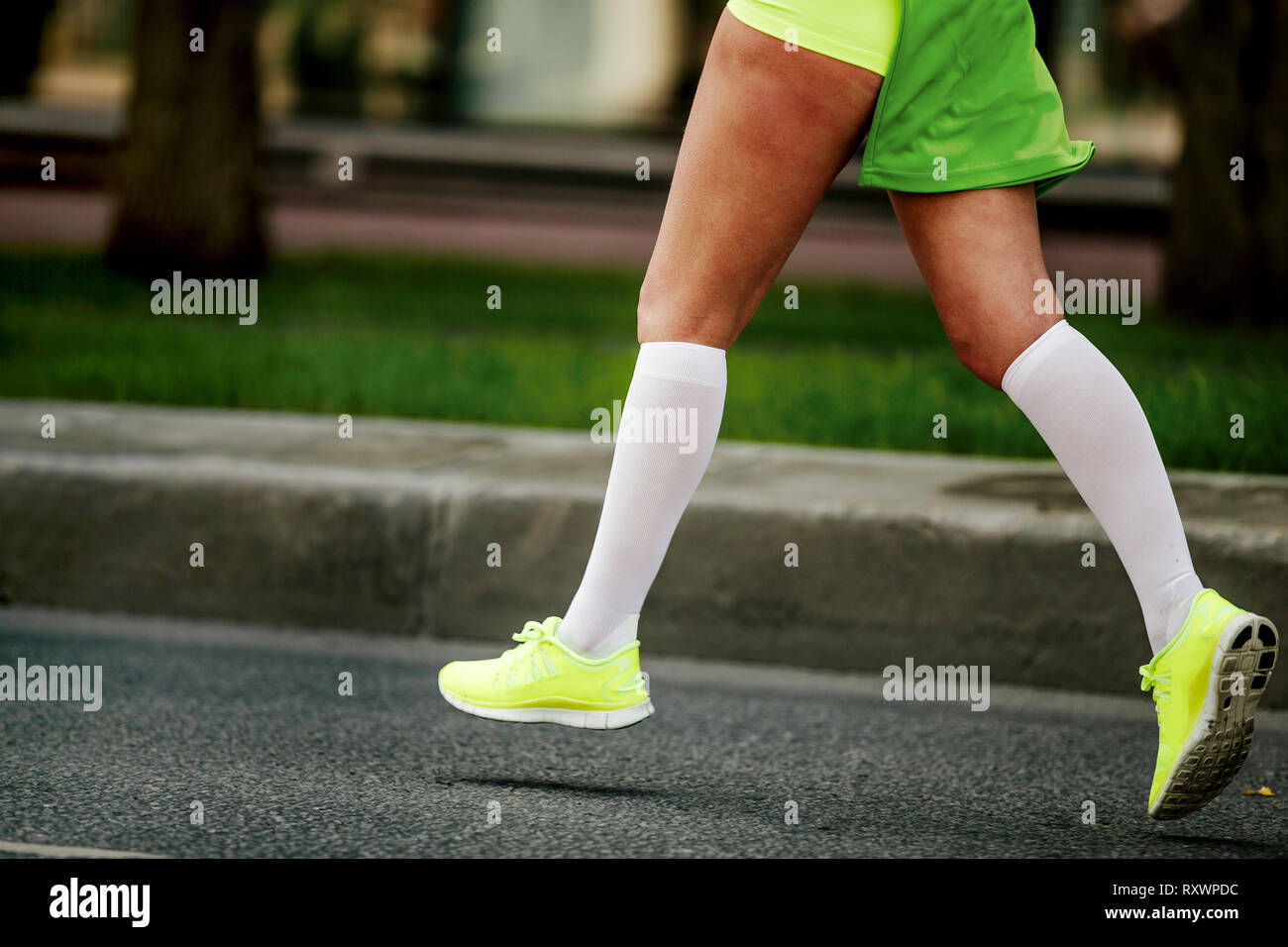 women feet in white compression socks and bright green running shoes Stock Photo