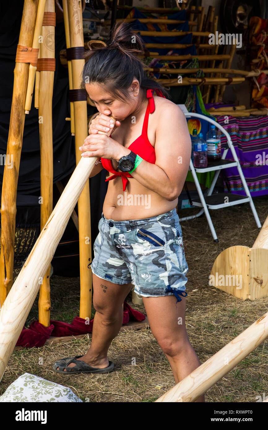 Girl playing didgeridoo at Into the Wild festival, Kent, UK Stock Photo