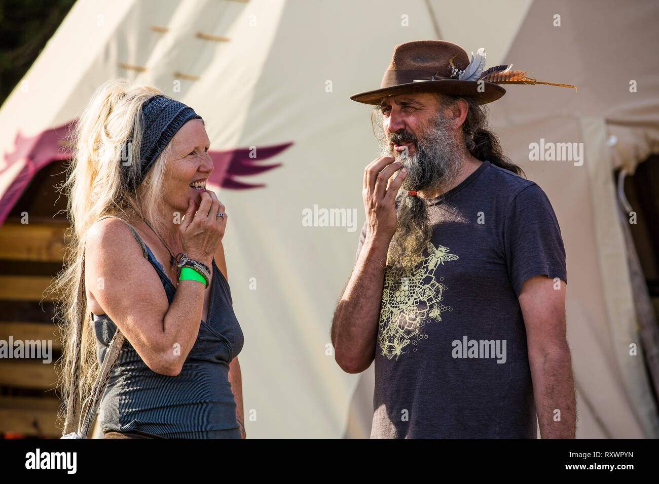 Man with long grey beard in a ponytail and lady talking at Into the Wild festival, Kent, UK Stock Photo