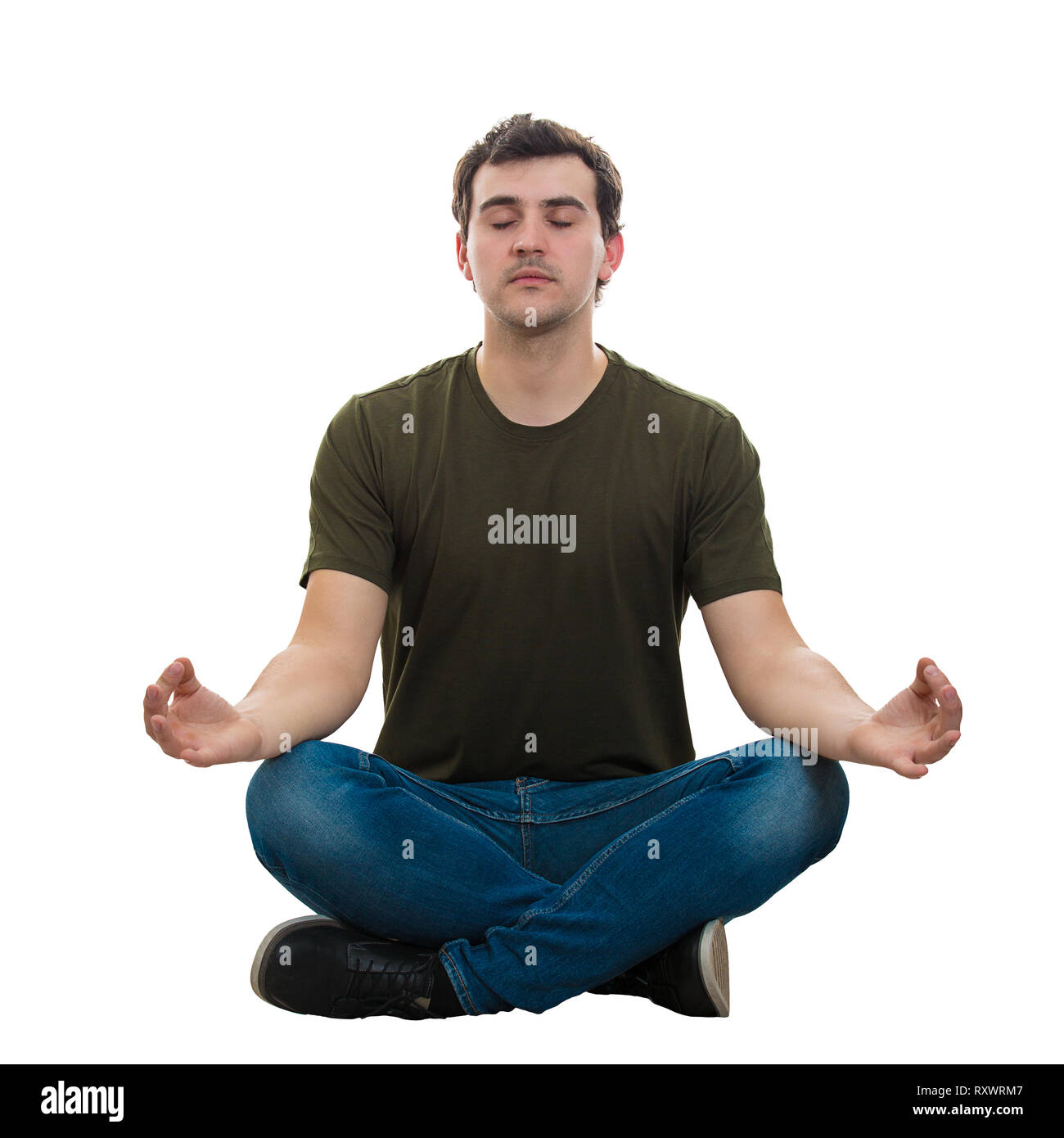 Casual young man sitting on the floor eyes closed and crossed legs and raising hands showing zen gesture like practicing yoga. Relaxed guy meditate an Stock Photo