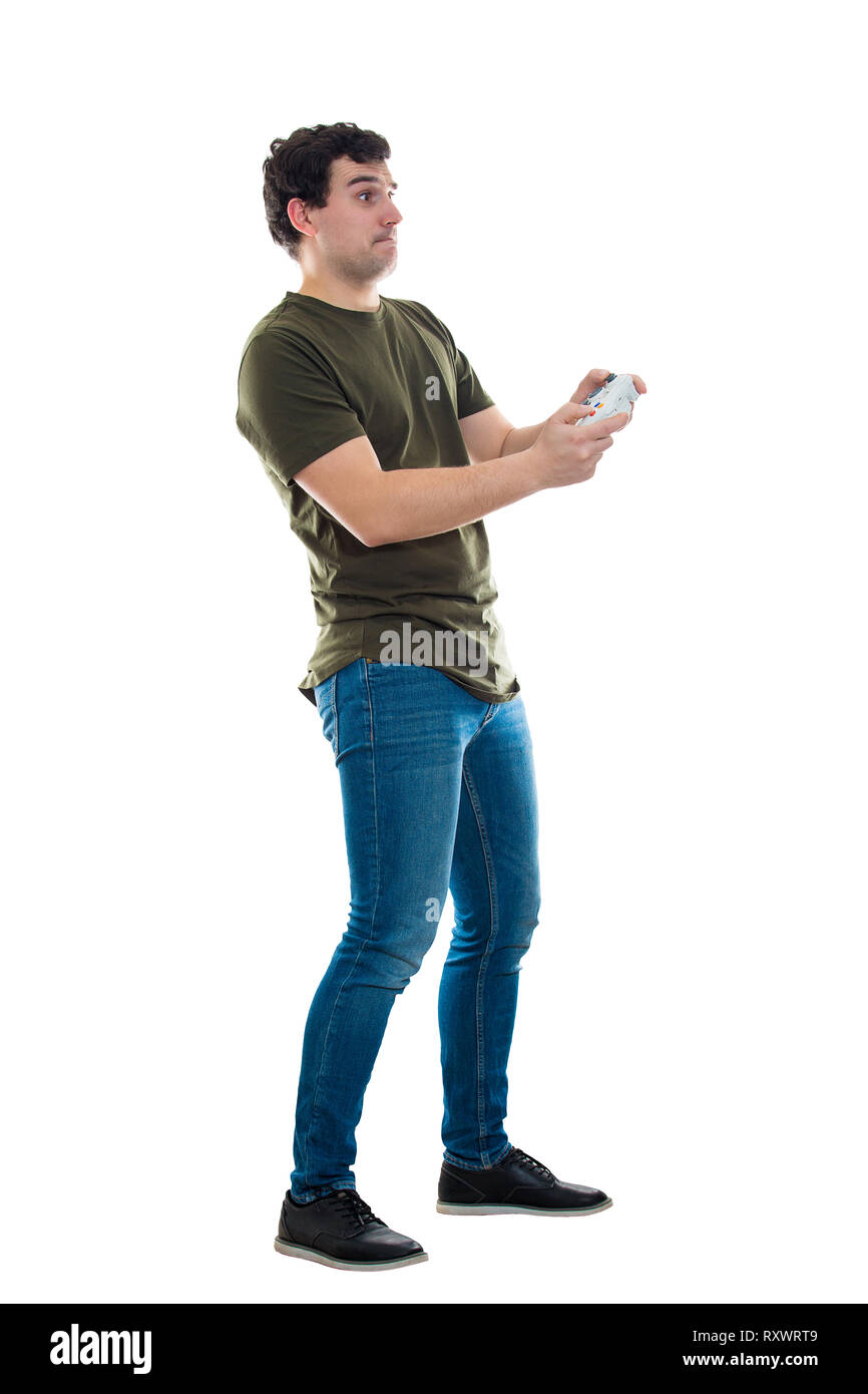 Addicted young man playing video games isolated over white background. Excited guy stand all ears holding a joystick console looking attentive try to  Stock Photo