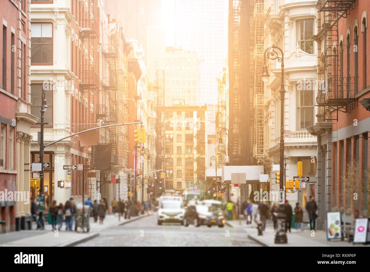 Busy intersection of Broome and Greene Streets is crowded with people and cars in the SoHo neighborhood of New York City with sunlight background Stock Photo