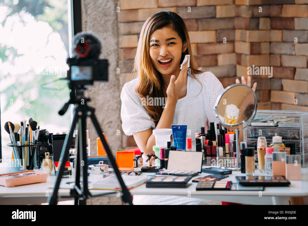 Charming Asian girl recording vlog. Beauty blogger presenting makeup  cosmetics in front of camera Stock Photo - Alamy