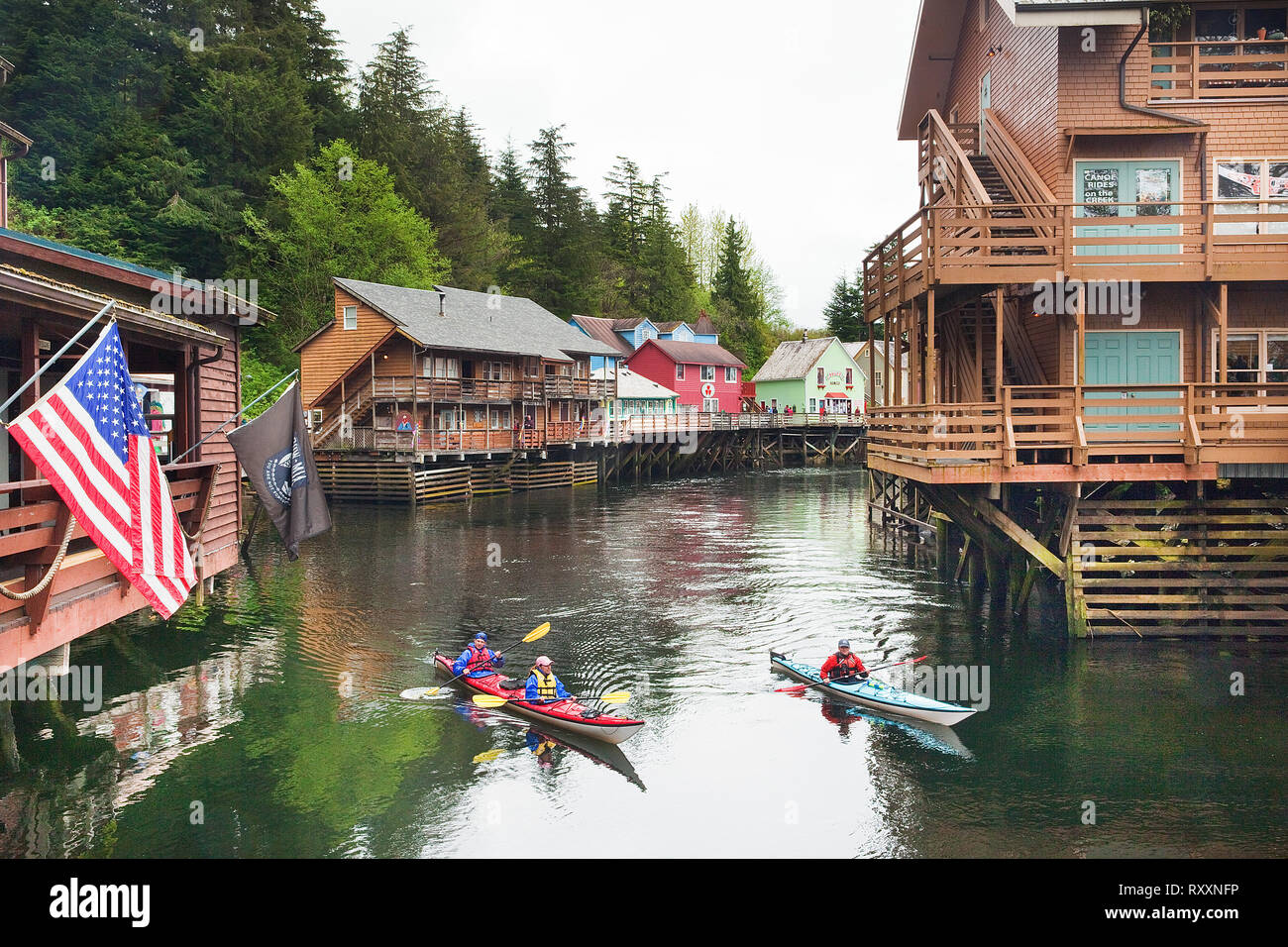 Kayakers paddling up Ketchikan Creek amidst the town's formerly 'infamous' Creek Street district, now a popular tourist area where the shops are perched on pilings. Ketchikan, Alaska, USA Stock Photo