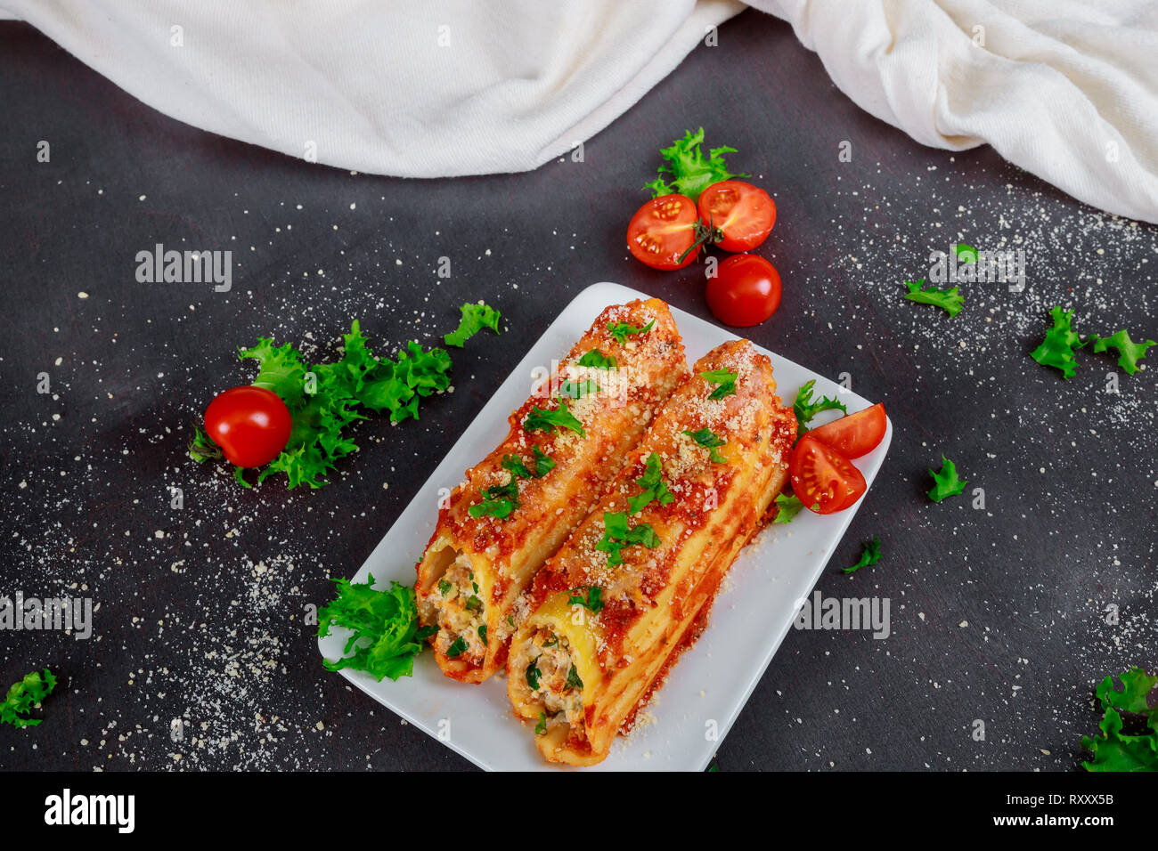 Traditional Italian rondelli cannelloni pasta with tomato sauce on rustic background Stock Photo