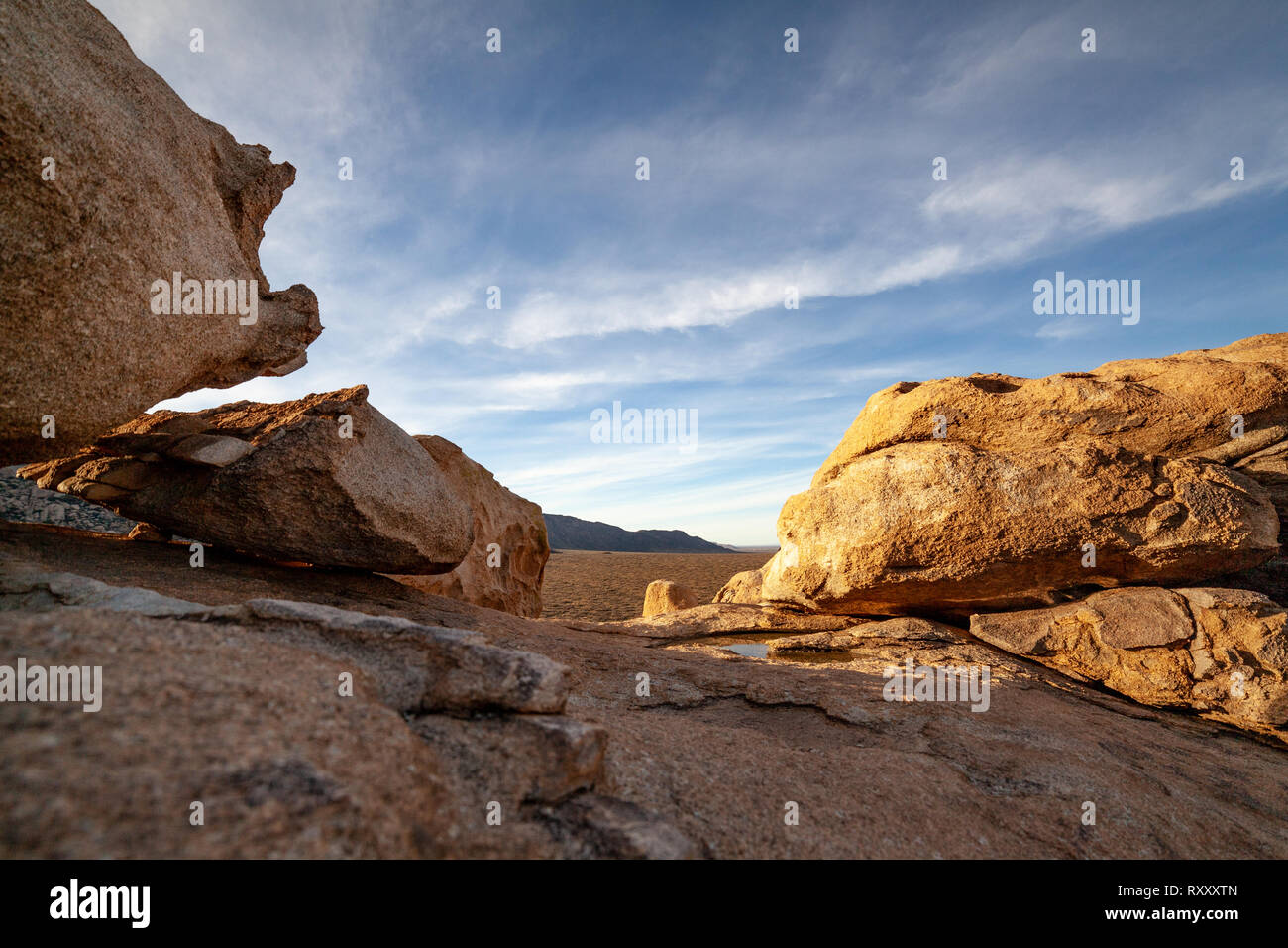 Golden sunlight spills over rugged desert rocks. Stock Photo