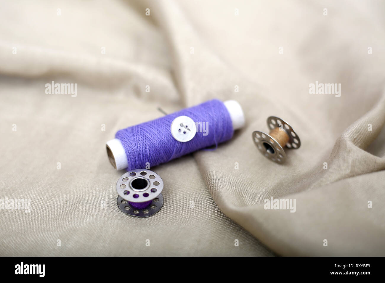 Photo of One thread, button and one bobbin on the cloth Stock Photo - Alamy