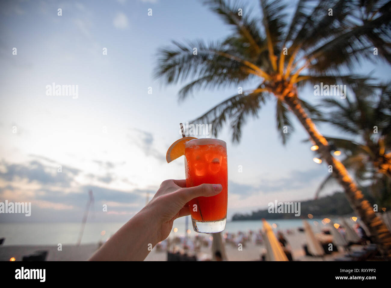 Crop hand with beverage on beach Stock Photo