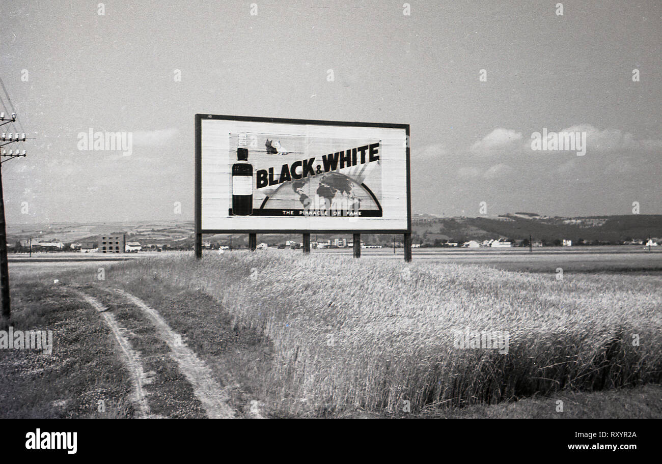 1930s, Czechoslovakia, historical picture from this era of a large billboard or advertising sign for 'Black and White' scotch whisky in a field beside the country's new Autostradu or motorway. Stock Photo