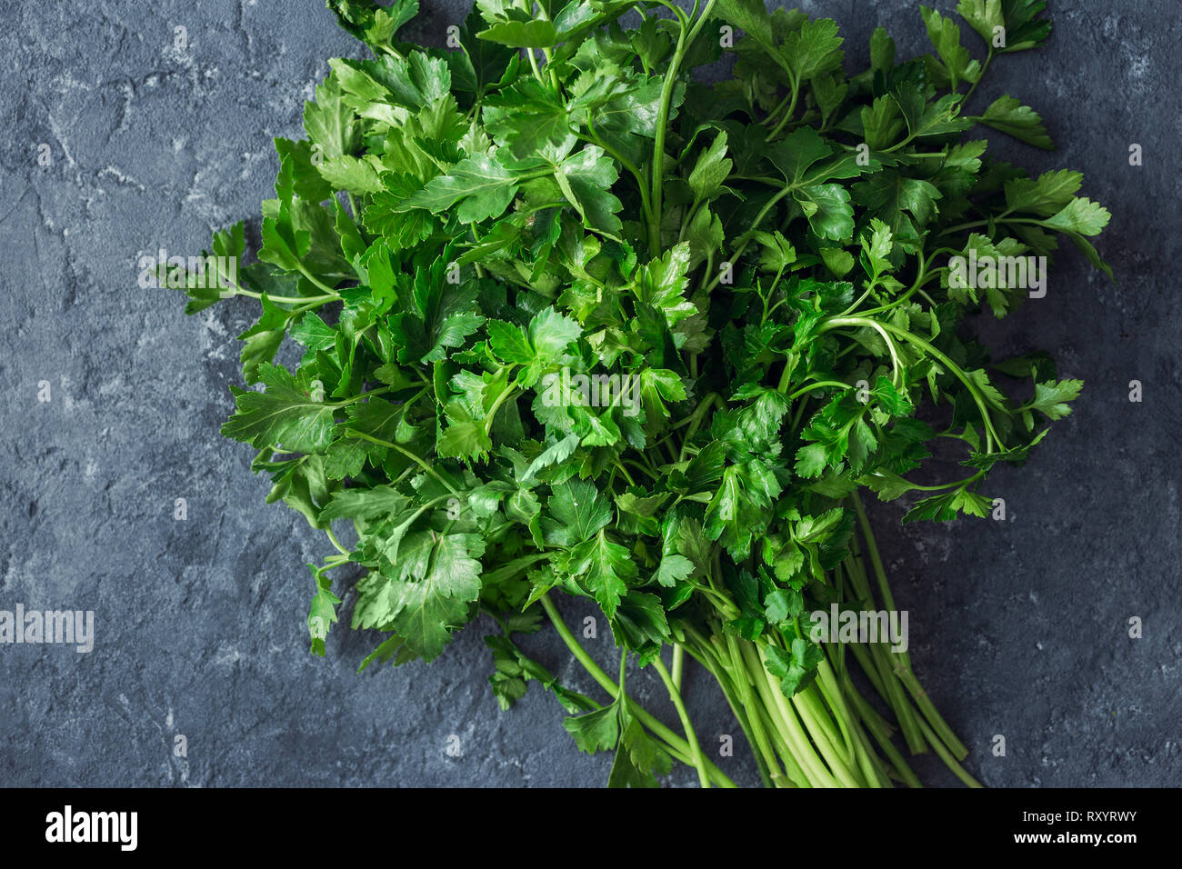 Bunch of parsley on dark stone background top view Stock Photo