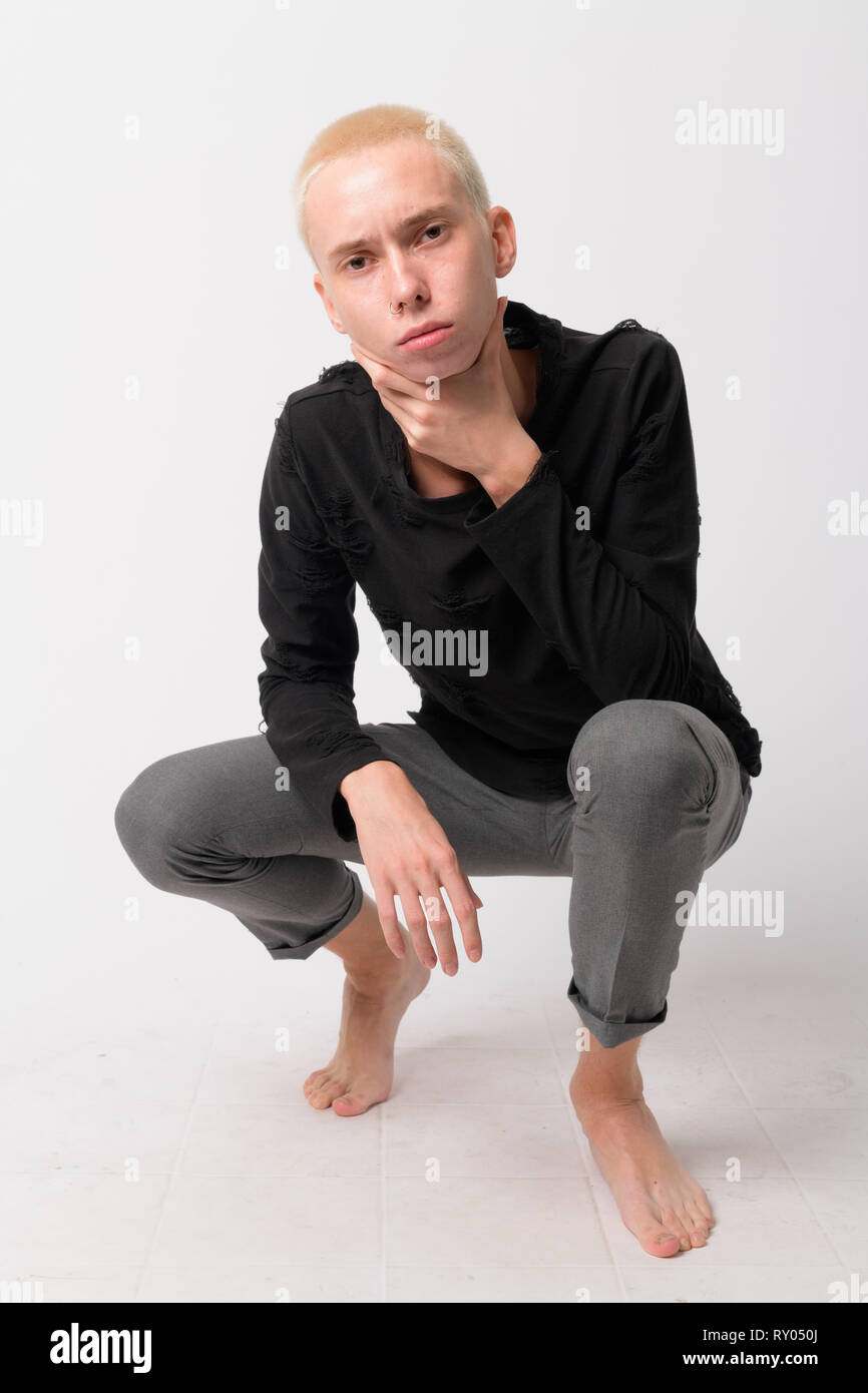 Full body shot of young androgynous man crouching and looking at camera ...