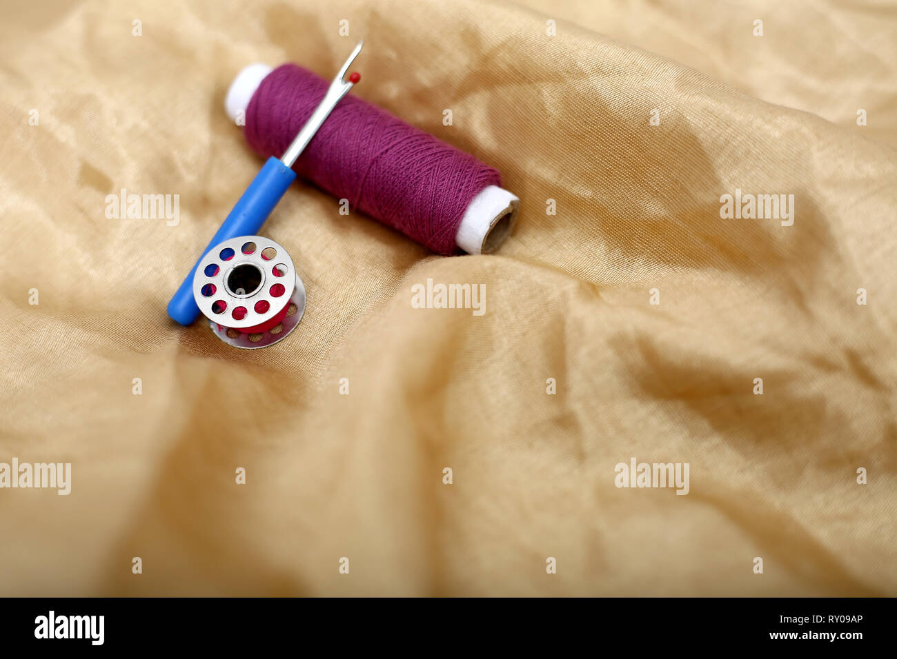 Picture of one sewing thread, needle ripper and bobbin on the