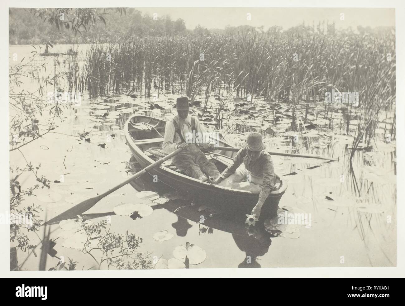 Gathering Water-Lilies. Peter Henry Emerson; English, born Cuba, 1856-1936. Date: 1886. Dimensions: 19.7 × 29.1 cm (image/paper); 28.6 × 41 cm (album page). Platinum print, pl. IX from the album 'Life and Landscape on the Norfolk Broads' (1886), edition of 200. Origin: England. Museum: The Chicago Art Institute. Stock Photo