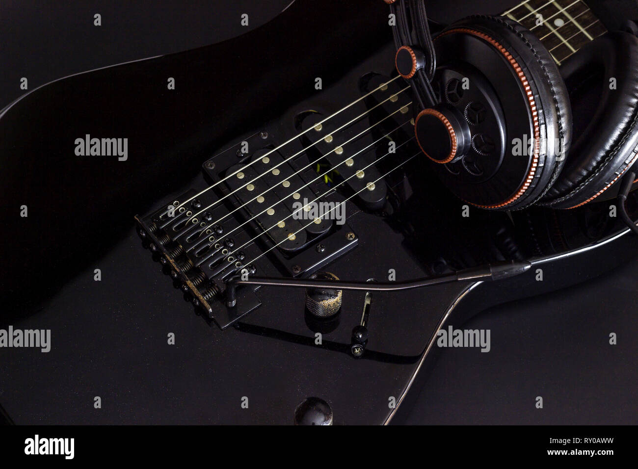 Headphone on black electric guitar in darkness Stock Photo Alamy