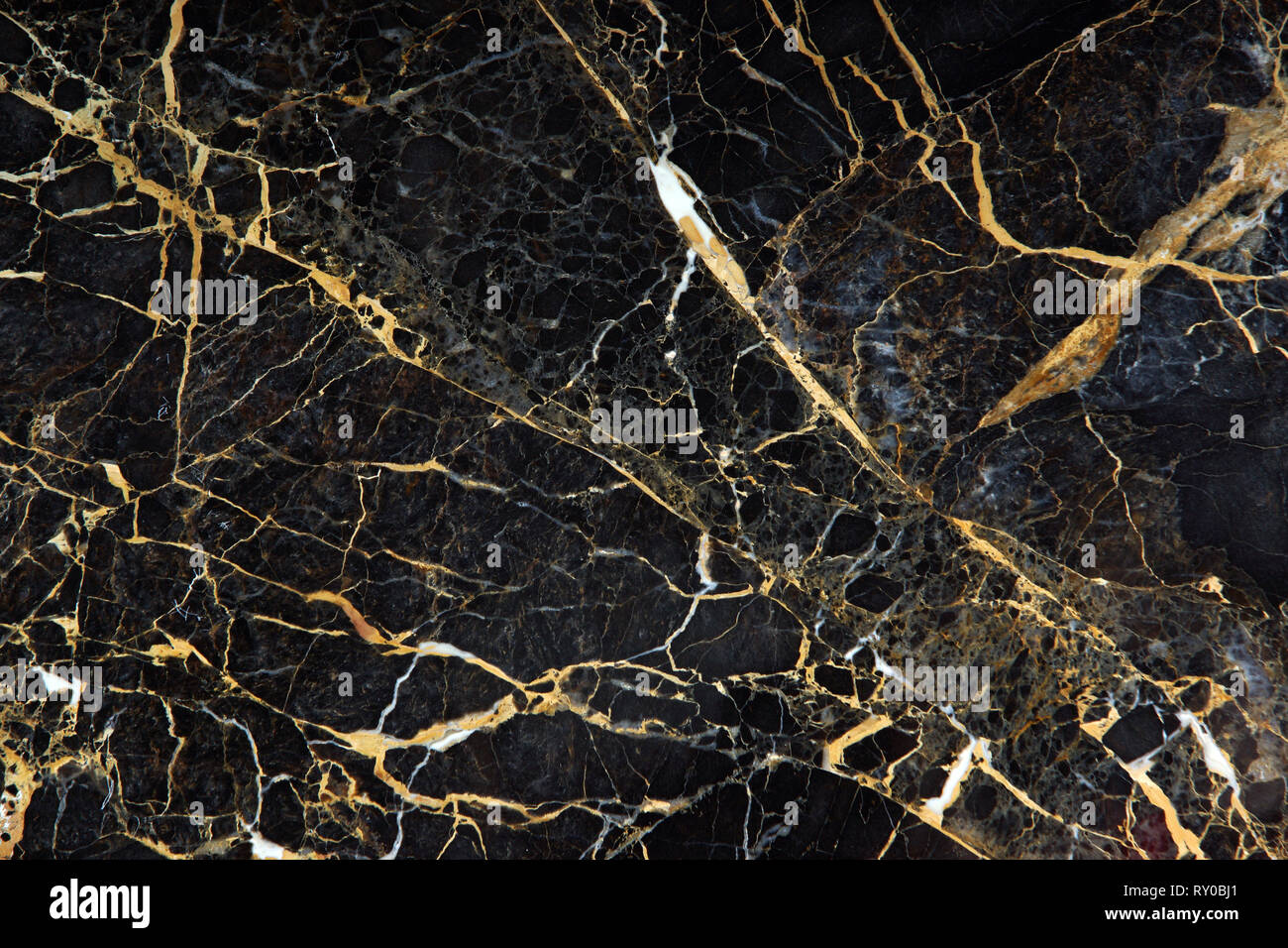 The surface of the slab of dark expensive marble with yellow and white