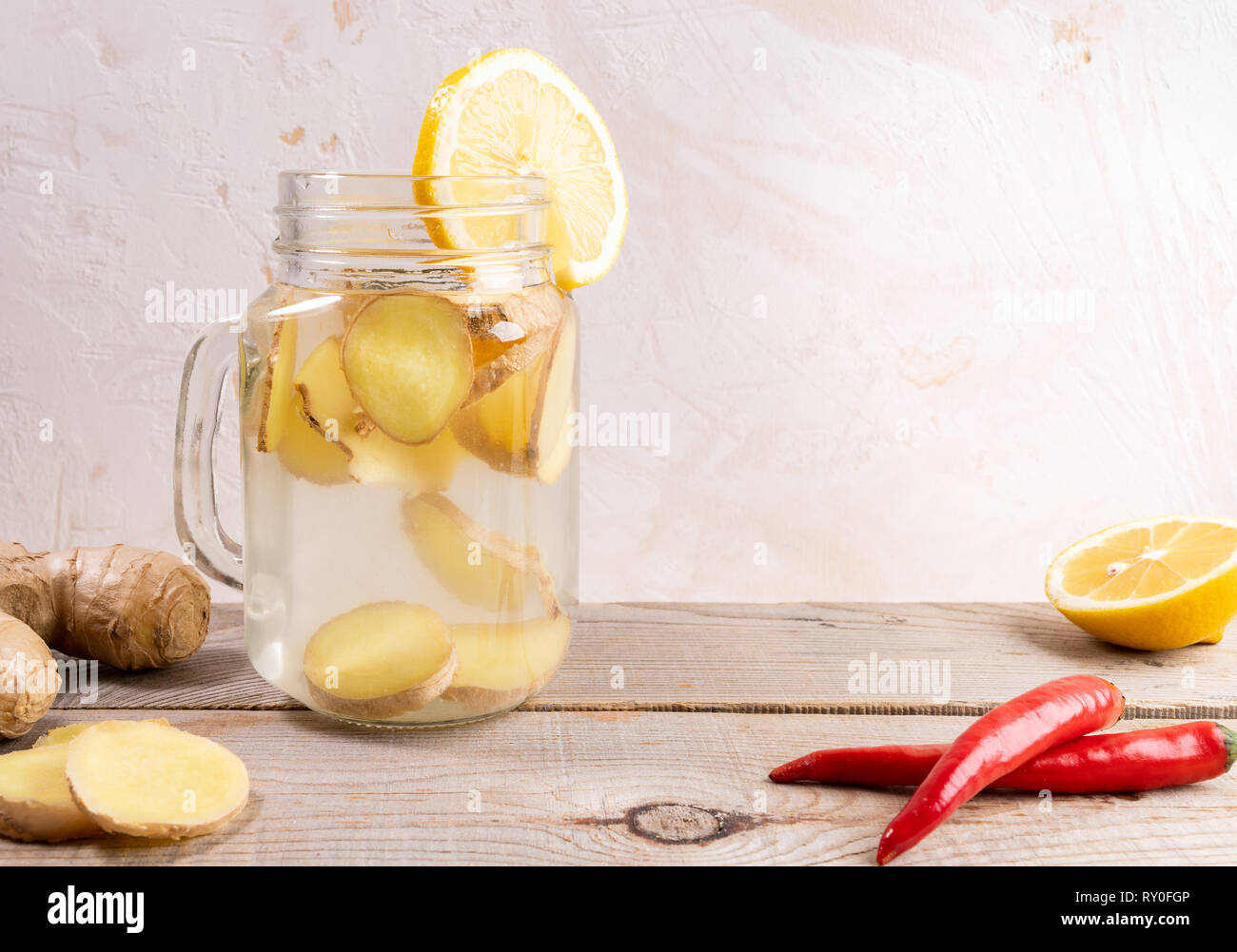 Glass jar full with ginger water and spises on wooden table on light background.  Stock Photo