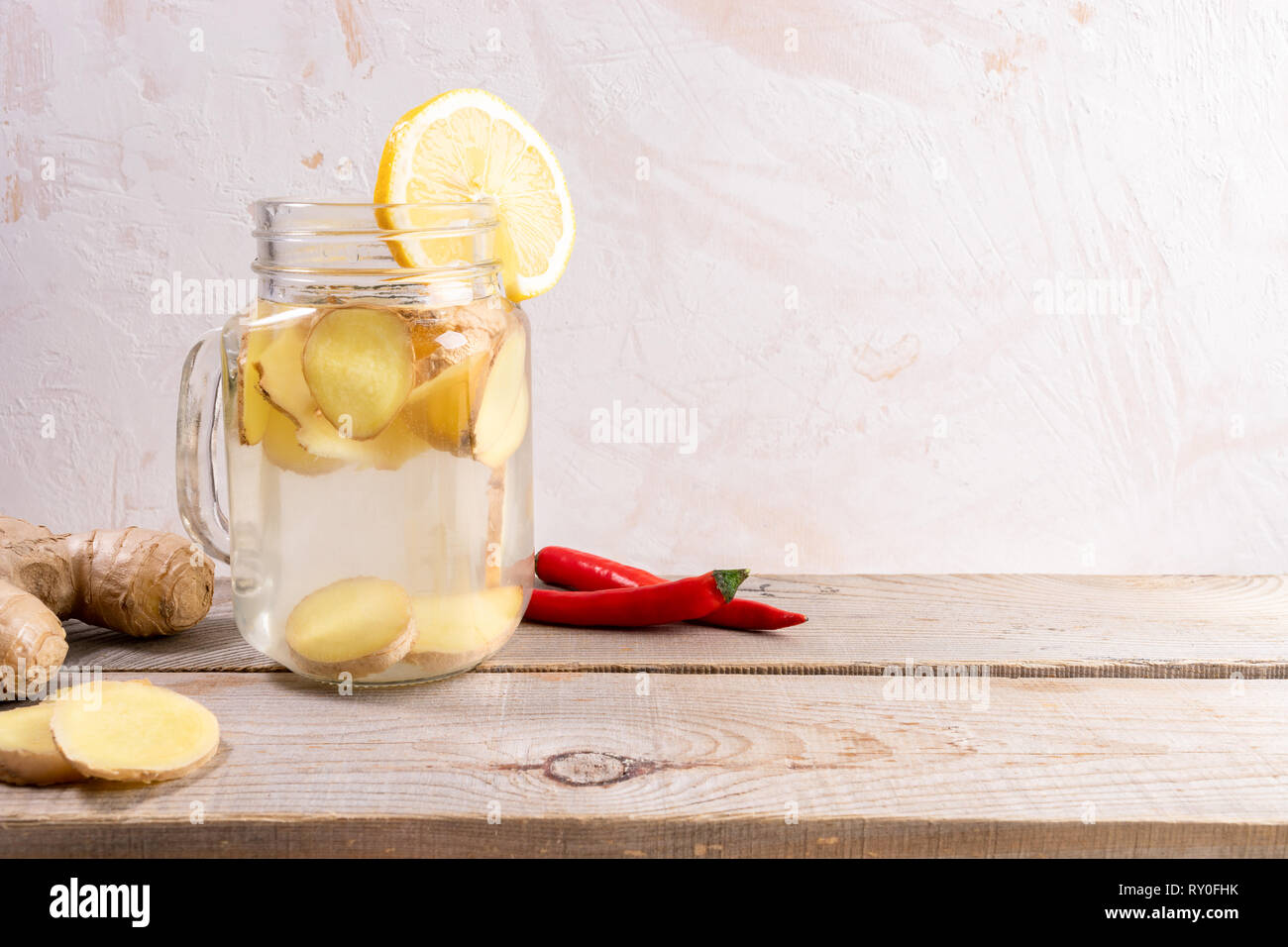 Glass jar with ginger water on wooden table on light background with copy space.  Stock Photo