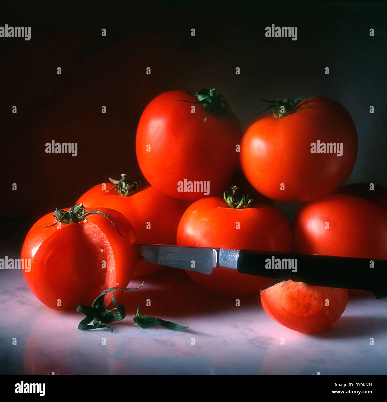 Bunch of tomatoes and knife in a slice on a marble table Stock Photo