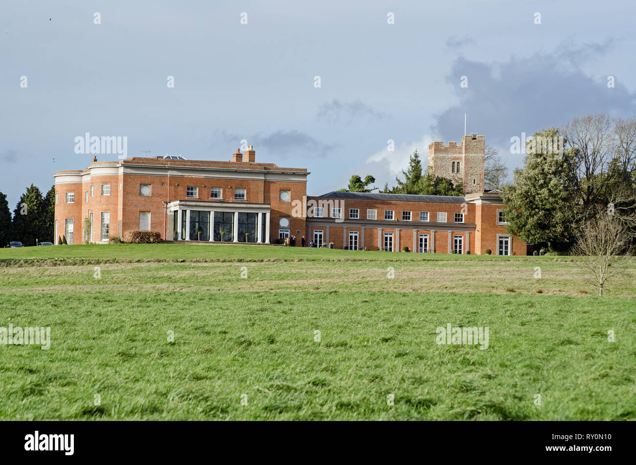 View across pasture towards the historic Queen Anne style stately home of Highfield Park in Heckfield, Hampshire.  Former Prime Minister Neville Chamb Stock Photo