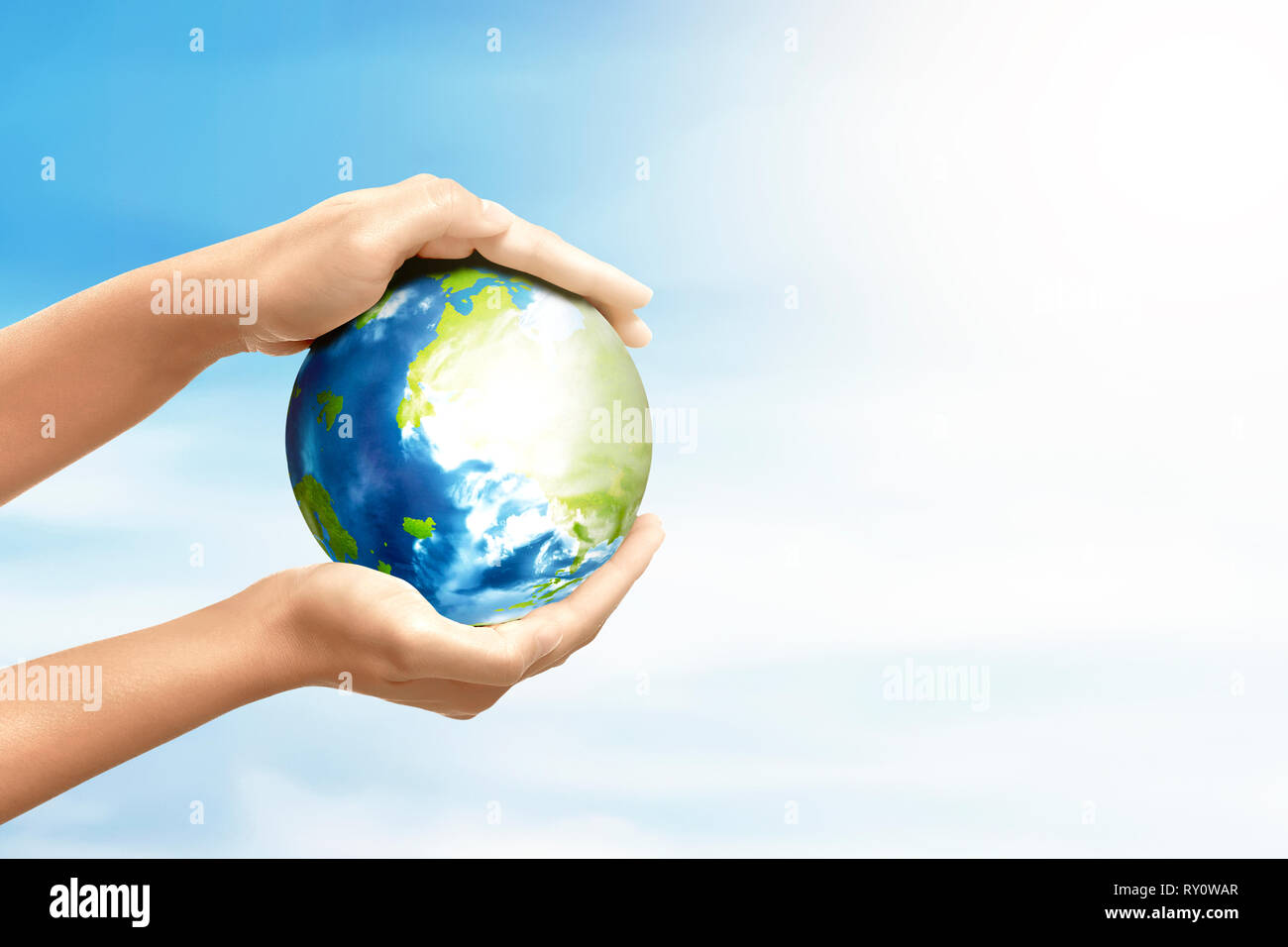 Hands holding earth planet over blue sky background. Earth hour concept Stock Photo