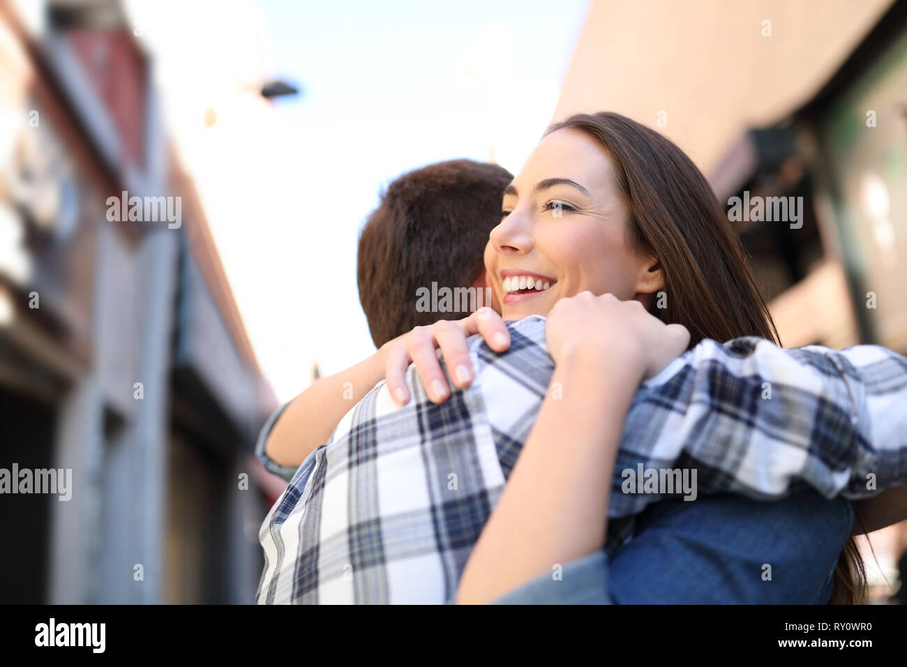 Happy couple or friends hugging after meeting in the street Stock Photo