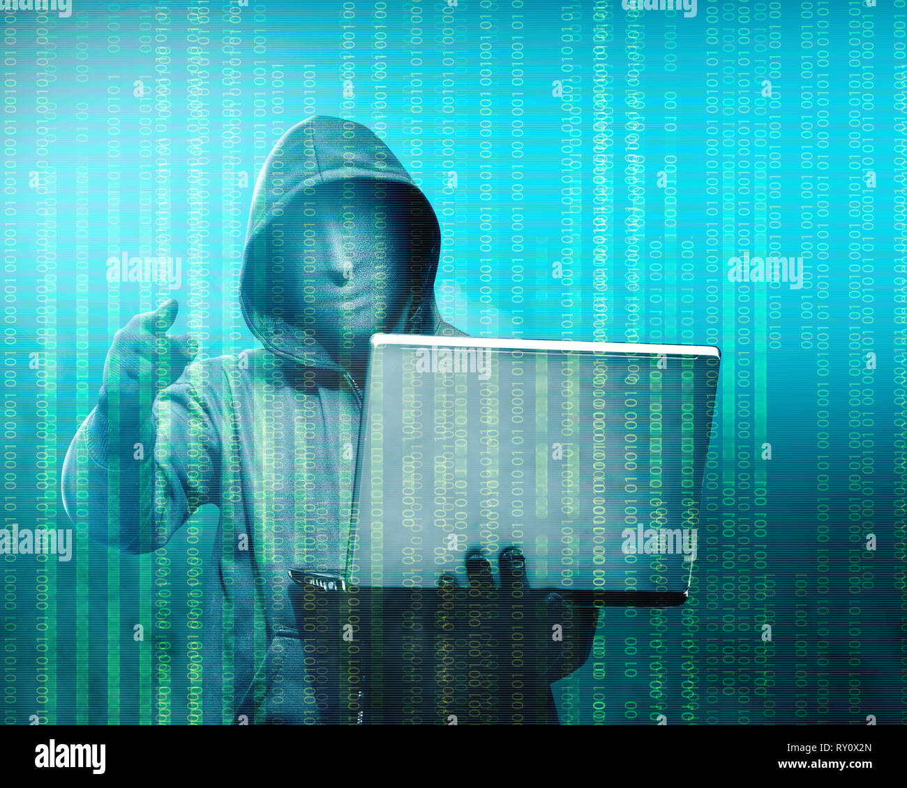 Hacker in black hoodie holding laptop with his hand and pointing to you with binary code on green background Stock Photo
