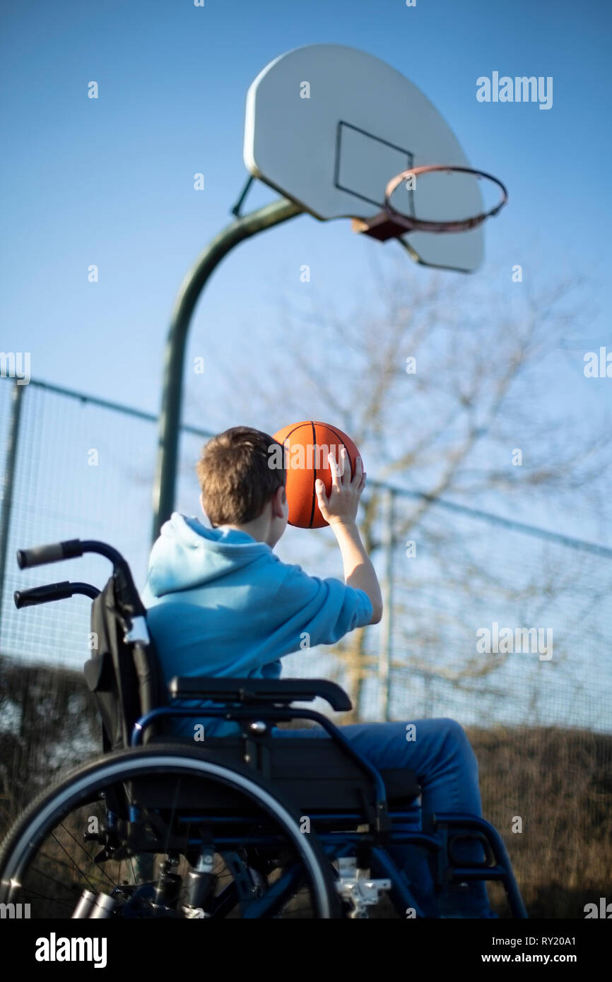 Teenage Boy In Wheelchair Playing Basketball Shooting Hoop Stock Photo