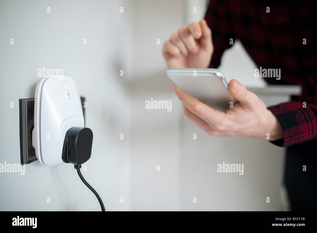 Man Controlling Smart Plug Using App On Mobile Phone Stock Photo