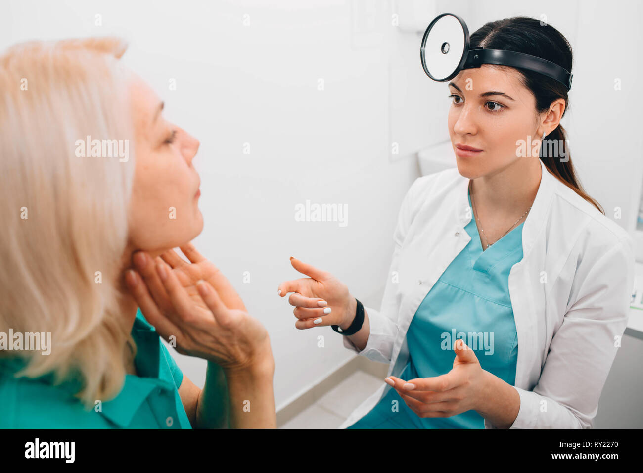 Mature patients showing pain at Throat to her otolaryngologist. Medical exam Throat and consultation. Stock Photo