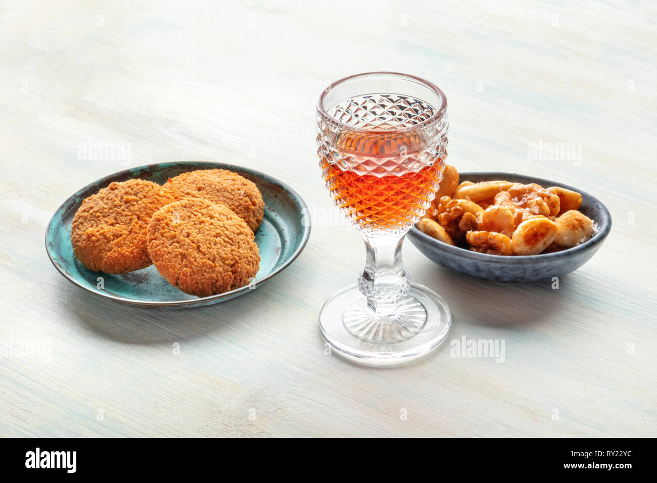 A photo of a glass of fortified wine with cookies and nuts, with copy space Stock Photo
