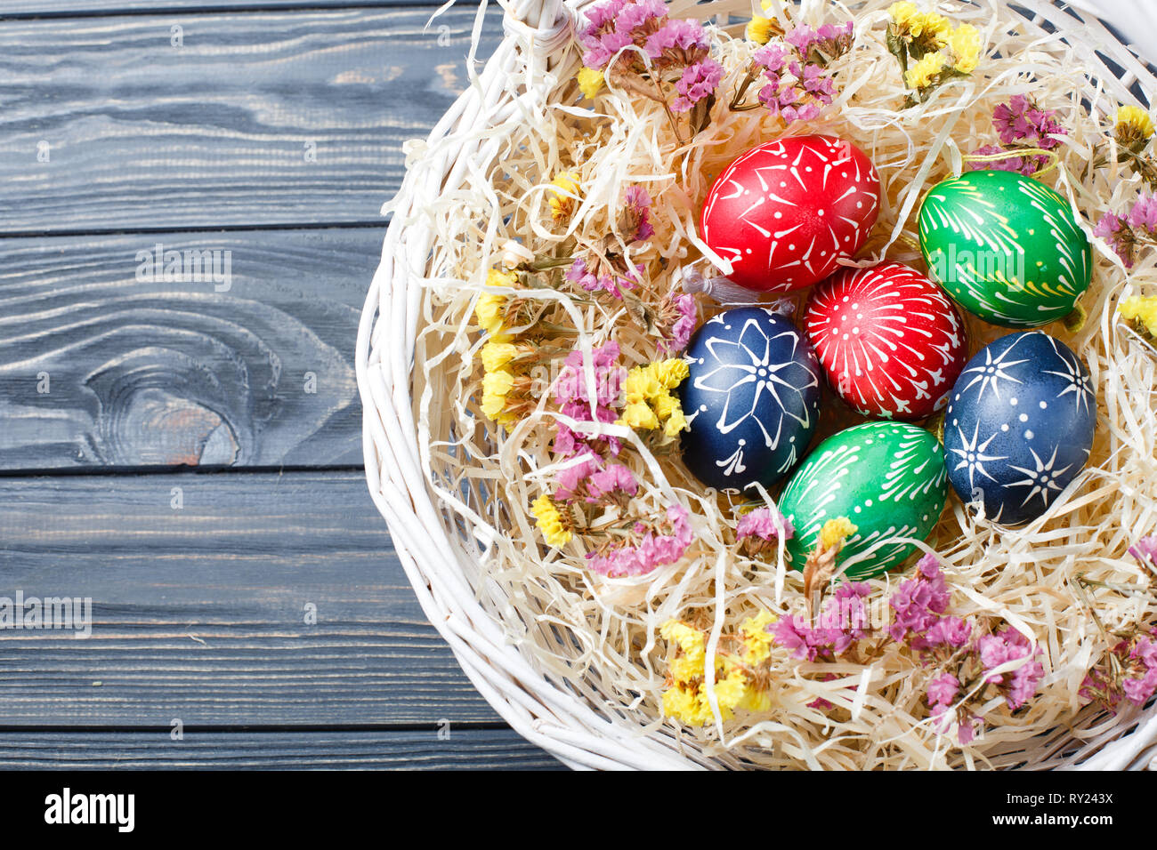 Hand painted different colors easter eggs in nest and flowers on grey ...