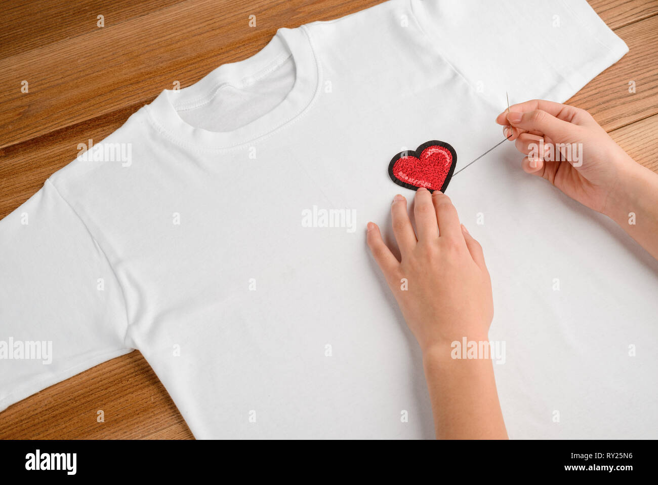 Girl applying embroidered heart patch Stock Photo