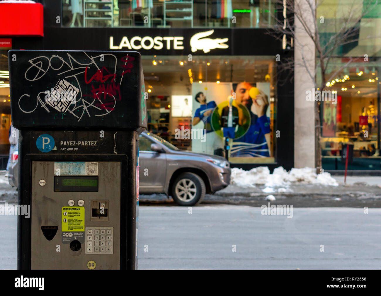 Montreal, Quebec, Canada-March 9 2019: Parking payment station in montreal downtown with lacoste logo in background Stock Photo