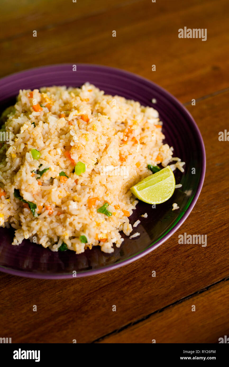 Fresh fried jasmine rice with egg and vegetables served with lime