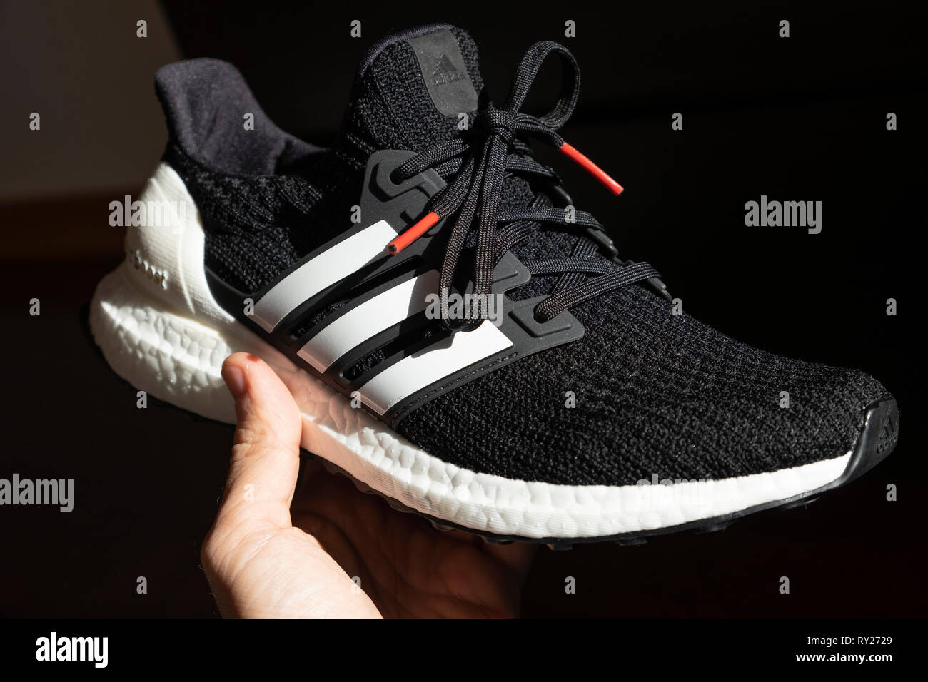 Person holding a black Adidas Ultraboost running shoe Stock Photo - Alamy