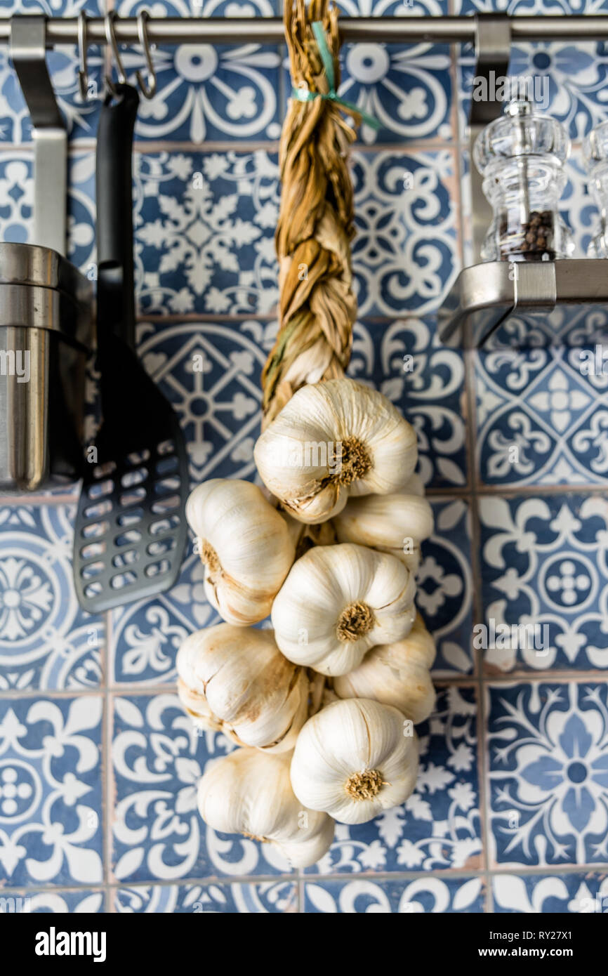 garlic braid hanging on wall of pattern tiles Stock Photo
