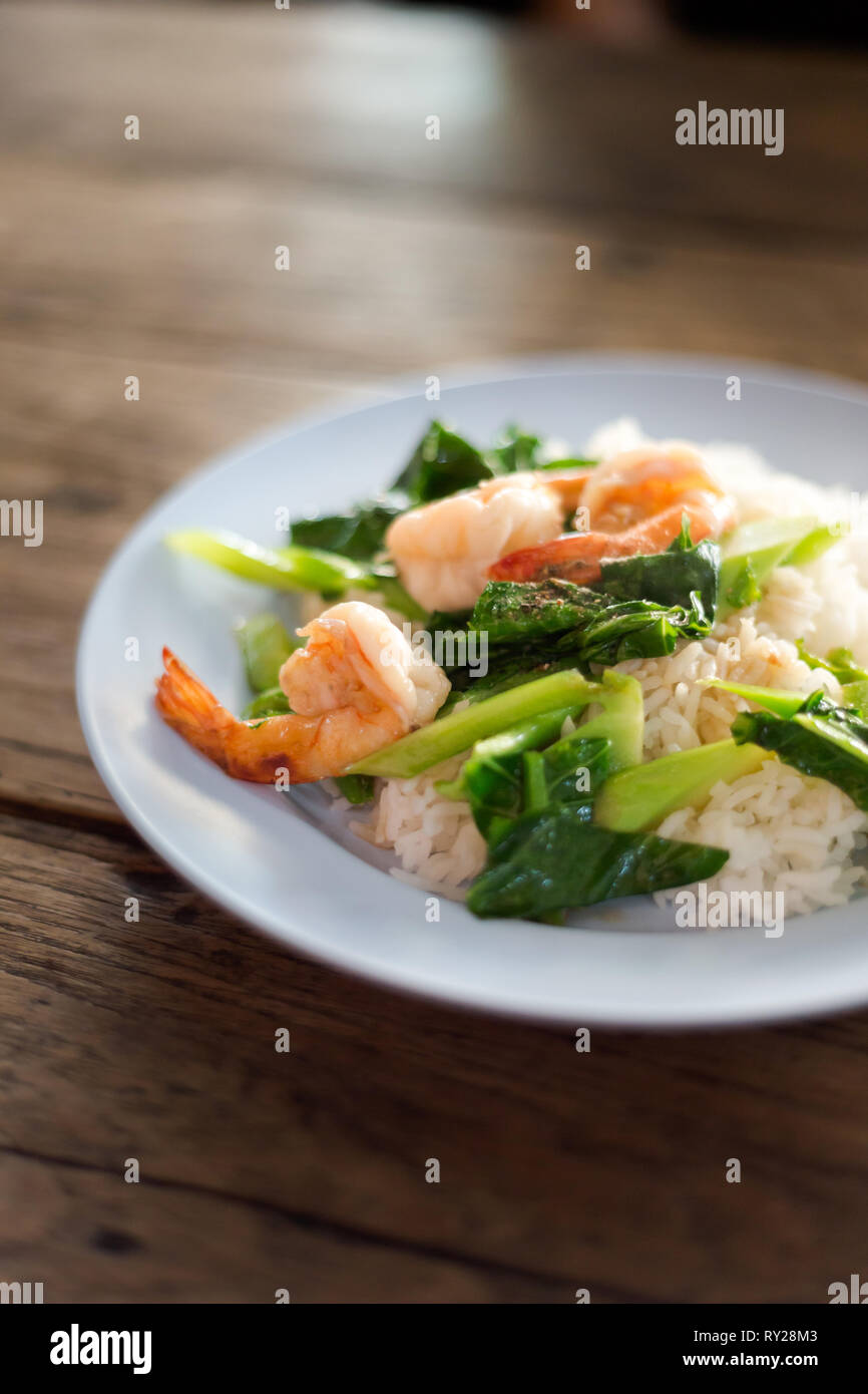 Thai fried kale with shrimps served on steamed rice. Traditional south east asian cuisine. Stock Photo