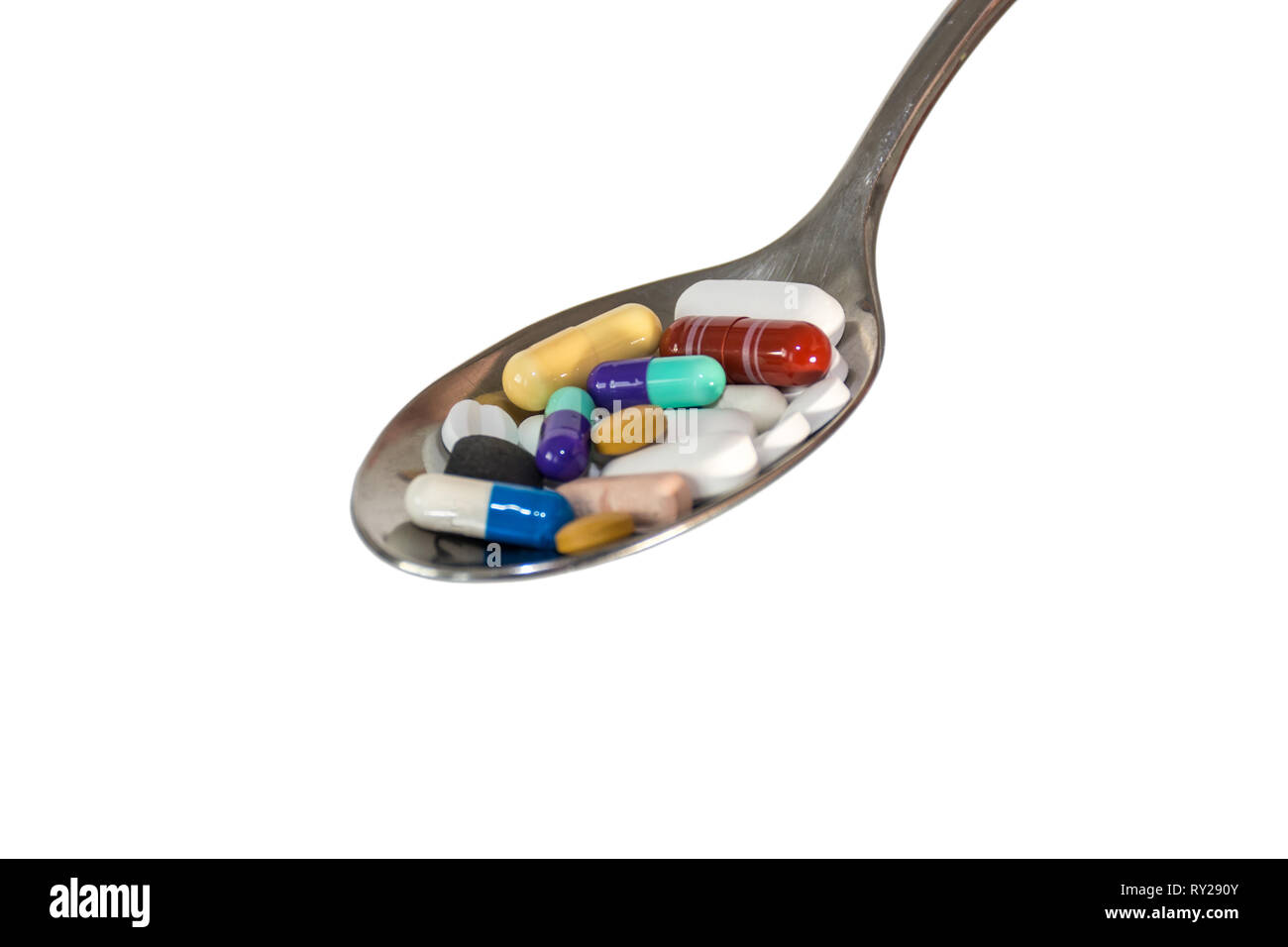 colored medicine pills on a teaspoon isolated on white background Stock